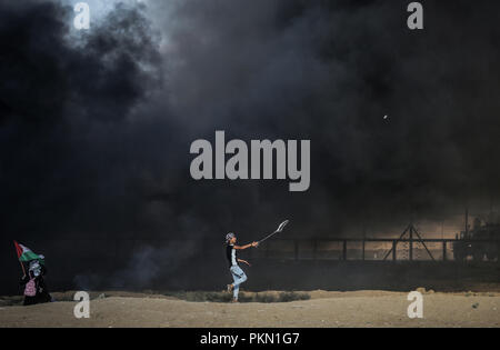 Gaza, Gaza, Gaza. 14 Sep, 2018. Ein palästinensischer Mann mit einer Schleuder Steine gegen israelische Truppen während der Auseinandersetzungen zu werfen. Auseinandersetzungen zwischen palästinensischen Demonstranten und israelischen Kräfte während eines Protestes entlang der israelischen Zaun östlich von Gaza-stadt. Credit: nidal Alwaheidi/SOPA Images/ZUMA Draht/Alamy leben Nachrichten Stockfoto