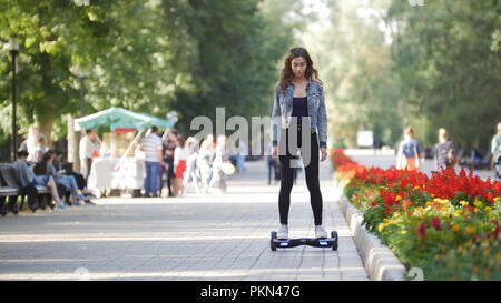 Junge schöne Mädchen reitet ein Kreisel im Park im Sommer Stockfoto