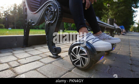 Mädchen nachdenklich auf der Bank sitzen im Park. Ihre Füße sind auf der Gyro. Sommer. Stockfoto