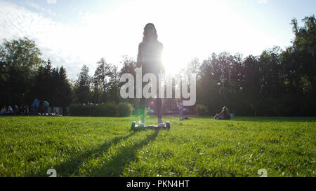 Ein junges Mädchen mit einem schönen Bild, einem Kreisel auf der Wiese im Park. Die Sonne scheint. Stockfoto