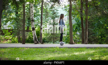 Schöne junge Mädchen reitet ein Gyro auf einem Pfad im Park unter den Bäumen, im Sommer Stockfoto