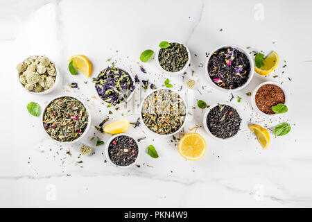 Sortiment von verschiedenen trockenen Tee - Classic Schwarz und Grün, Blumen, Obst, Beeren und Kräuter Tee Mischungen, mit Zitrone und Minze, weißem Marmor Hintergrund kopieren Stockfoto