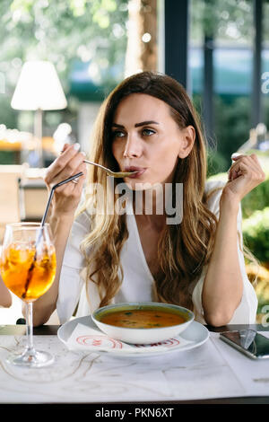 Junge attraktive Frau essen Suppe im Restaurant