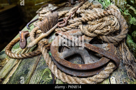 Verworfen, alte Werkzeuge, einschließlich einer Riemenscheibe und Seil auf einer hölzernen Werkbank. Stockfoto