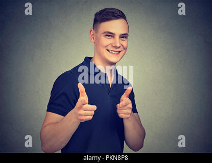 Inhalte positiv Mann an der Kamera zeigt mit Fingern cool aussieht und wie auf grauem Hintergrund Stockfoto