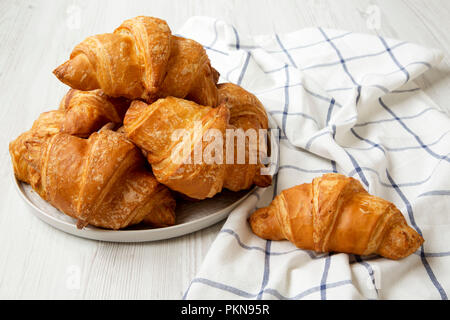 Frisch gebackene Croissants auf Grau runde Platte auf weiße Holztisch, Seitenansicht. Stockfoto