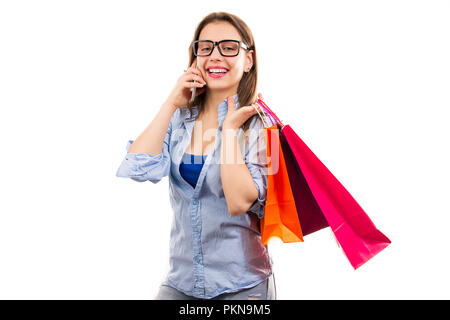 Freundliche moderne junge Frau mit bunten Tüten und sprechen am Telefon auf weißem Hintergrund Stockfoto