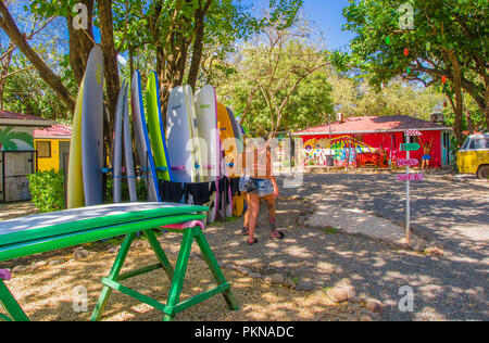 Tamarindo, Costa Rica, Juni, 26, 2018: Im freien Blick auf wunderschöne Frau Fuß Verleih in sonniger Tag und mit blauem Himmel in entspannenden Strand von Tamarindo, Surfbrett Stockfoto