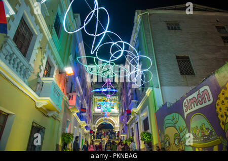 QUITO, ECUADOR - August, 15, 2018: die Masse von Menschen zu Fuß in einer engen Straße in ein Spektakel der Lichter auf den Wänden mit einigen beleuchteten Figuren während der Quito licht Festival projiziert Stockfoto