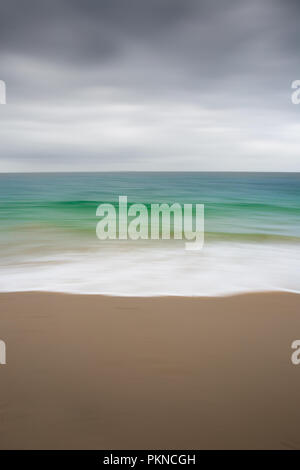 Ein Hintergrund Bild von einem smaragdgrünen Meer und Sandstrand in Cornwall, UK mit einem panning Technik eine glatte blur Effekt mit Kopie zu verursachen. Stockfoto