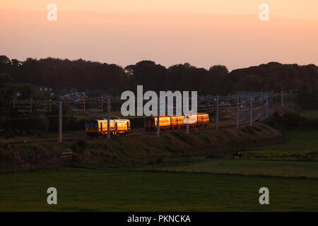 Northern Rail Class 156 Sprinter Züge, die eine Klasse 142 Pacer bei Kirkham & Wesham auf der Preston zu Blackpool Bahnstrecke funkeln bei Sonnenuntergang Stockfoto