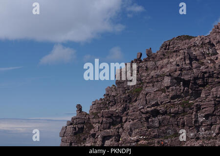 Ein Blick auf die höheren West End von Stac Pollaidh vom unteren Peak mit einer Kletterpflanze im Blick und den Felsvorsprung vor blauem Himmel Stockfoto