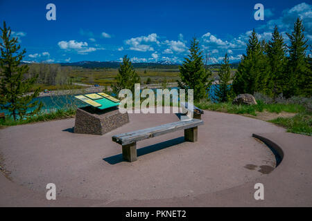 YELLOWSTONE, Montana, USA Mai 24, 2018: Die Schöne im Hinblick auf informative unterzeichnen und Holz- öffentlichen Stuhl mit Blick auf Jackson Lake Dam im Grand Teton National Park Stockfoto