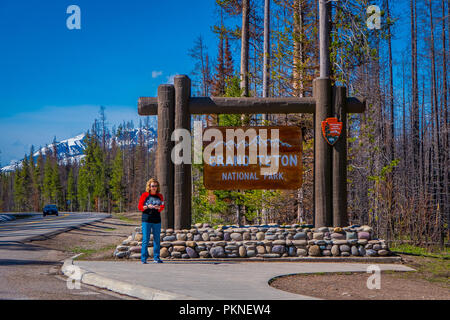 YELLOWSTONE, Montana, USA, 24. Mai 2018: Nicht identifizierte Frau in einer informativen Zeichen des Grand Teton im Yellowstone National Park warten Stockfoto