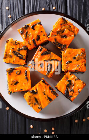 Festliche Halloween köstliche süße Dunkle brownie Kuchen mit orange Kürbis Creme in der Nähe eingerichtet - bis auf einen Teller. Vertikal oben Ansicht von oben Stockfoto