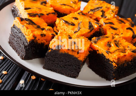 Original Chocolate Brownie Kuchen mit orangen Käsekuchen close-up auf einem Teller. Festliches Essen. Horizontale Stockfoto