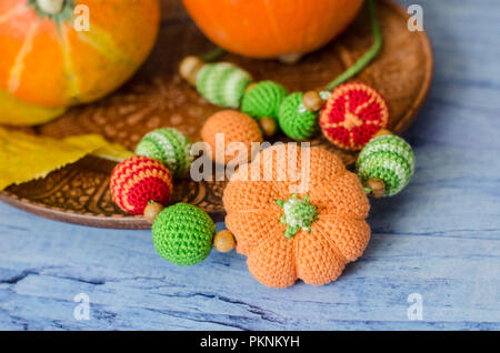 Halskette aus Gewirken Perlen für ein Kind in der Schlinge zu sitzen. Zusammensetzung der dekorative Kürbisse. Stockfoto