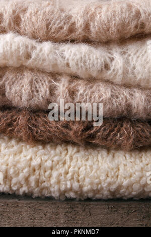 Warme gestrickte Pullover. Stapel aus Gewirken Kleider auf warmen Hintergrund, Pullover, Strickwaren, Vertikal, Herbst Winter Konzept Stockfoto