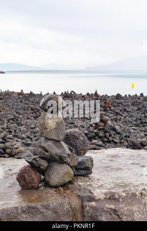 Zen - wie Cairns aus Lavagestein von Touristen gebaut auf der Uferpromenade in Reykjavik, mit Blick über die Bucht von Faxa auf die Halbinsel Snaefellsnes, Island Stockfoto