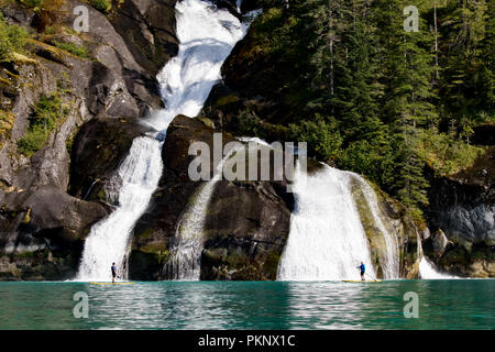 Stand up Paddle Boarding vor einem großen Wasserfall in der Eiszeitlich geschnitzt von Tracy Arm Fjord im Südosten Alaska USA Stockfoto