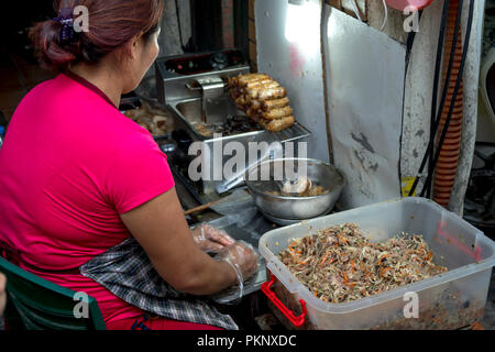 Eine Frau, die Frühlingsrollen auch als Nem zu den Touristen auf den Straßen von Hanoi zu verkaufen. Vietnamesische Küche. Stockfoto