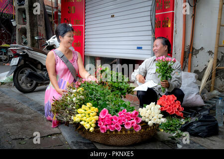 Szene zwei Glücklich lächelnde Frauen kaufen frische Blumen auf einer alten Straße in Hanoi, Vietnam Stockfoto