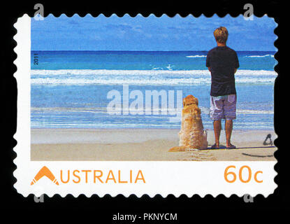 Australien - ca. 2011: Stempel in Australien lebenden australischen dedizierte gedruckt, zeigt jungen Mann mit seinem Hund auf das Meer, ca. 2011 Stockfoto