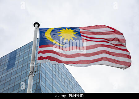 Malaysia Fahne. Malaysische Flagge auf einer Stange winken, modernes Bürogebäude Hintergrund Stockfoto