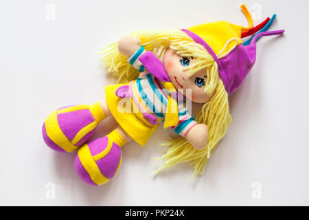 Rag Doll weiches Kuscheltier in farbenfrohem Gelb und Lila Lila Outfit auf weißem Hintergrund gekleidet Stockfoto