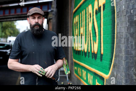 Artist Lionel Stanhope unter einer Eisenbahnbrücke neben Selhurst Bahnhof, South London, der street artist wandelt einige von Londons&Otilde; s-bahn Brücken zu Kunstwerken. Stockfoto