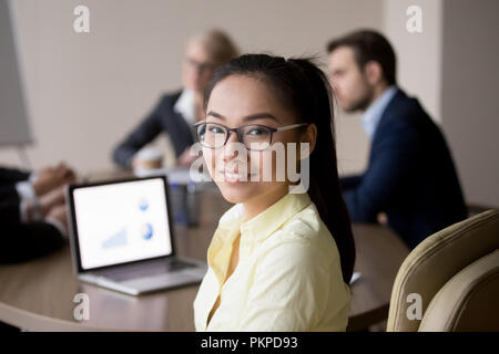 Asiatische Frau am Schreibtisch im Büro an Kamera suchen Stockfoto