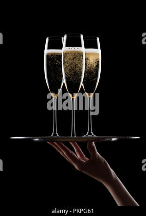 Hand hält Tablett mit gelben Champagner Gläser mit Blasen auf schwarzem Hintergrund Stockfoto