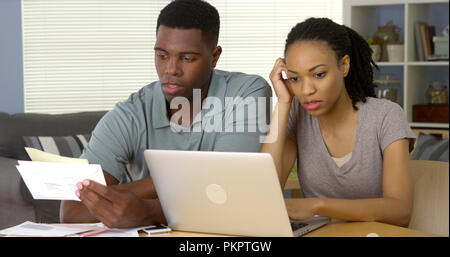 Frustrierte junge Schwarze Paar über Rechnungen und Finanzen online Stockfoto