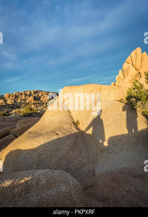 Schatten der zwei Leute auf einem Felsen in der Joshua Tree National Park, Kalifornien, USA Stockfoto