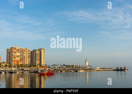 Weißen Leuchtturm und den hohen Gebäuden Malaga mit ihren Reflexionen in Malaga, Spanien, Europa im Golden Sunset Stunde Stockfoto