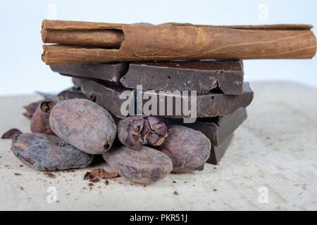 Leckere dunkle Schokolade und Kakao Bohnen auf einem weißen Tisch. Süßigkeiten verwendet Desserts in der Küche vorzubereiten. Weißer Hintergrund. Stockfoto