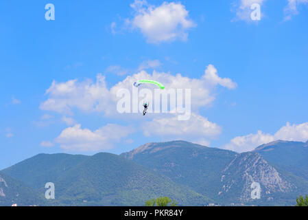 Fallschirmspringer steigt vor blauem Himmel, im Hintergrund die Berge Stockfoto