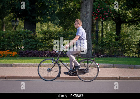 RIGA, Lettland - 18 JULI 2018: ein Mann mit einem Fahrrad entlang der Straße. Stockfoto