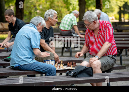 RIGA, Lettland - 18 Juli, 2018: Männer, die auf Parkbänken sitzen und spielen Schach. Stockfoto