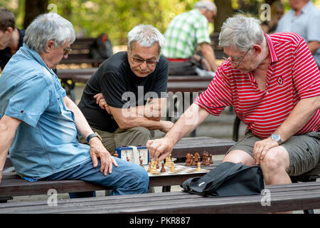 RIGA, Lettland - 18 Juli, 2018: Männer, die auf Parkbänken sitzen und spielen Schach. Stockfoto