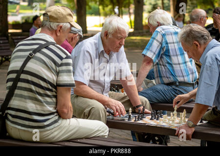 RIGA, Lettland - 18 Juli, 2018: Männer, die auf Parkbänken sitzen und spielen Schach. Stockfoto