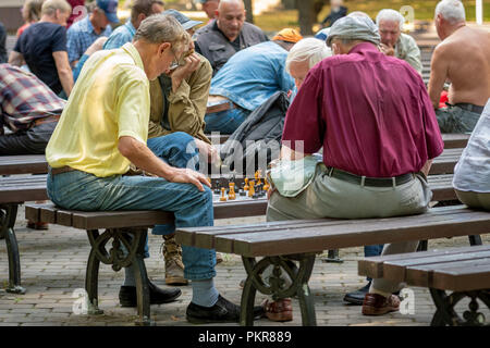 RIGA, Lettland - 18 Juli, 2018: Männer, die auf Parkbänken sitzen und spielen Schach. Stockfoto