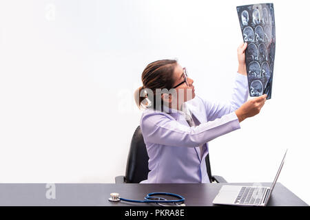 Junge Ärztin holding MRI oder CT-Bild, Arzt in Uniform sitzen im Arbeitsraum und Holding X-ray Bild für Diagnose Hirnverletzung oder Scannen Stockfoto