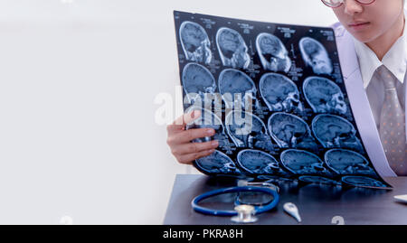 Junge Ärztin holding MRI oder CT-Bild, Arzt in Uniform sitzen im Arbeitsraum und Holding X-ray Bild für Diagnose Hirnverletzung oder Scannen Stockfoto