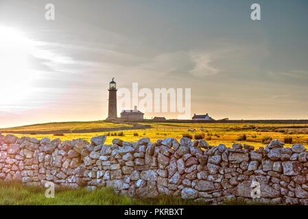 Die Sonne auf dem alten Leuchtturm auf Lundy Island, die umliegenden Felder und eine Trockenmauer Stockfoto