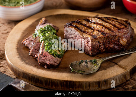 Eine köstliche Medium Feuer gegrillte Argentinien style Steak mit Chimichurri verde Sauce. Stockfoto