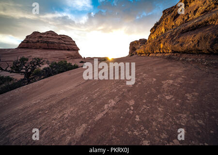 Wanderweg zum Zarten Arch im Arches Nationalpark in Utah bei Sonnenaufgang. Sunbeam nur über den Rand der Felsen Stockfoto