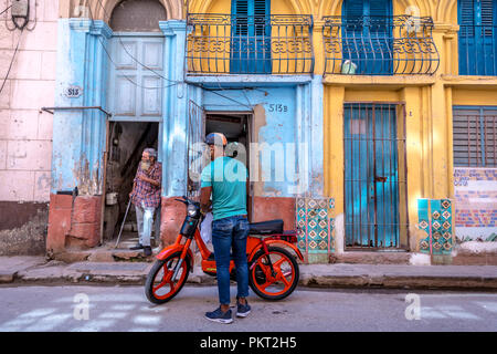 Kuba, Havanna - Mar 9 2018 - Lokale Bürger von Havanna Parkplatz eine alte, sehr einfache Motorrad vor einem alten, wenig Schäden Haus in Havanna, Kuba Stockfoto