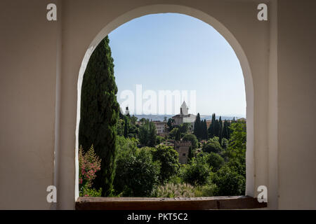 Blick auf den Glockenturm der Alhambra durch die rundbogenfenster aus den Gärten des Generalife in Granada, Spanien, Europa an einem hellen Sommertag Stockfoto