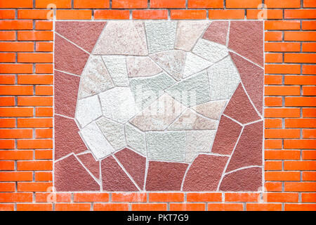 Schmuck der dekorativen Fliesen an der Wand aus rotem Backstein. Stockfoto